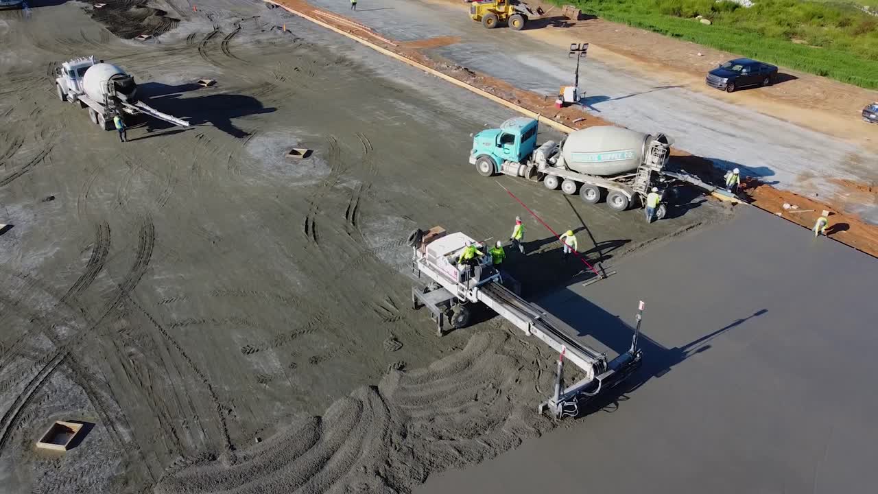 작업자는 콘크리트를 매끄럽게 하기 위해 중장비 스크리드 기계를 사용합니다.