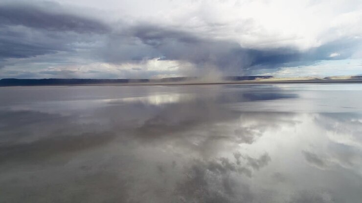 A high-flying, slow moving drone shot, of a storm and sand tornadoes forming over the salt flats of the Alvord Desert in Oregon