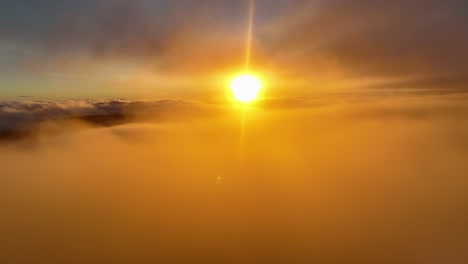 sun glowing through the foggy cloudscape, aerial view orange setting