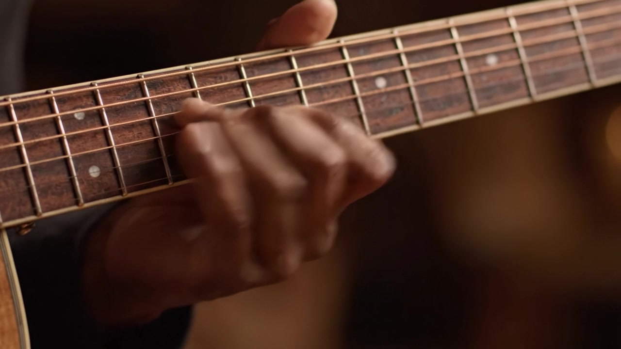 Primo piano della mano di un chitarrista abile che preme gli accordi su una chitarra acustica, catturando l'essenza dell'arte musicale e della passione in ogni movimento.