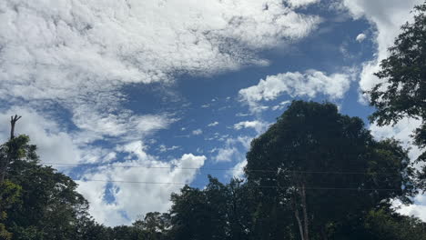 movement of white clouds against the blue sky in a village