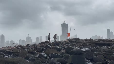 Two-Men-Walking-On-Pile-Of-Rock-With-Overcast-Sky-Due-To-Monsoon-In-India