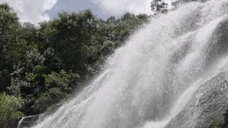 panning down over slow motion fast cascading waters from top of waterfall boulder terrain