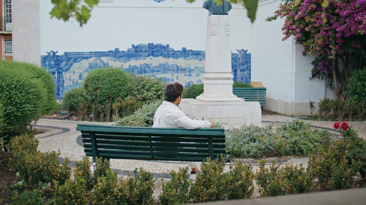 편안한 남자가 벤치에 앉아 시간을 보내고 도시 공원에서 마초가 정원 데이트를 기다리고 있습니다.