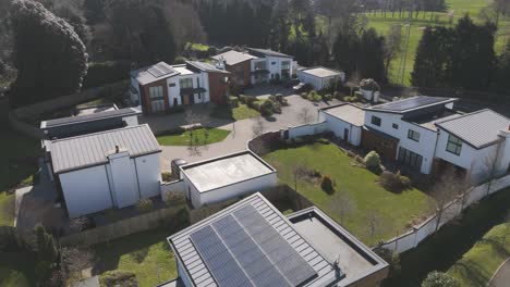 close aerial of angular grey-and-white houses with integrated garages and large solar arrays reflecting high-efficiency upscale living