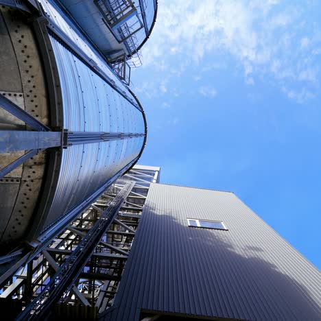 Storage tanks. Grain elevator on blue sky background. Large granary for agricultural crop. Close-up. Motion camera around.