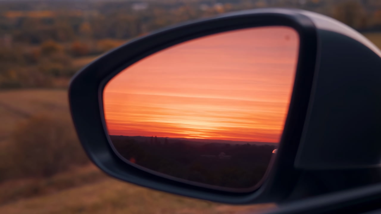 Sunset Reflected In Car Mirror, Warm Orange Horizon Visible In Glass, Blurred Countryside Outside, Calm