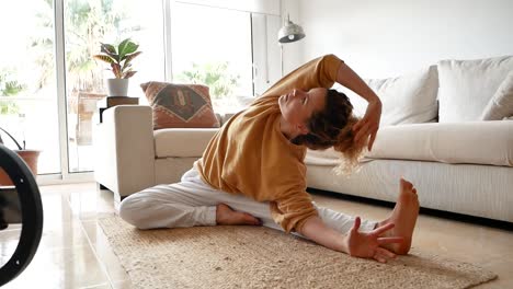 Fit-woman-sitting-on-floor-and-stretching-body-at-home