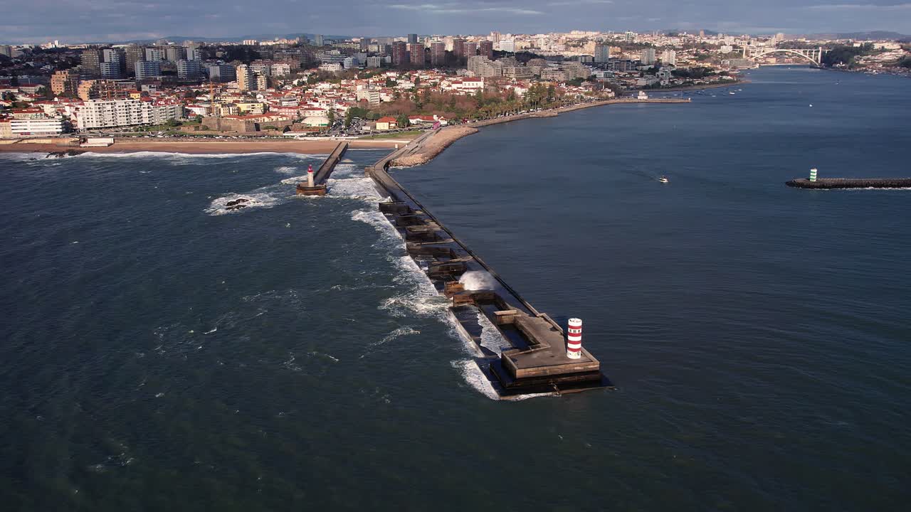Drone captures an expansive Porto coastal panorama featuring the historic breakwater fortification, city development on hillsides, sandy beach, and Atlantic waters in panoramic aerial view, Portugal