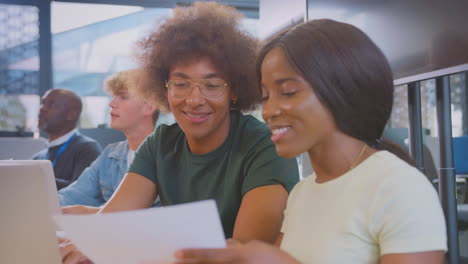university or college students sitting around table with tutor collaborating in seminar on laptop