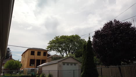 Wide-time-lapse-of-an-empty-urban-backyard-on-a-windy-day,-gradually-tilting-up-to-reveal-the-sky