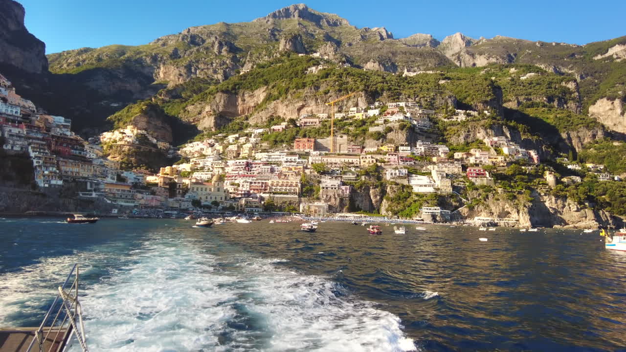 Vista della costa tirrenica a Positano, Italia. Edifici classici, barche galleggianti, vegetazione. Vista da una nave