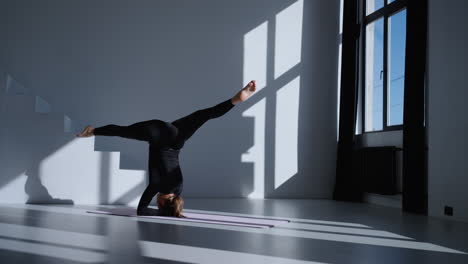 woman doing a handstand yoga pose in a studio