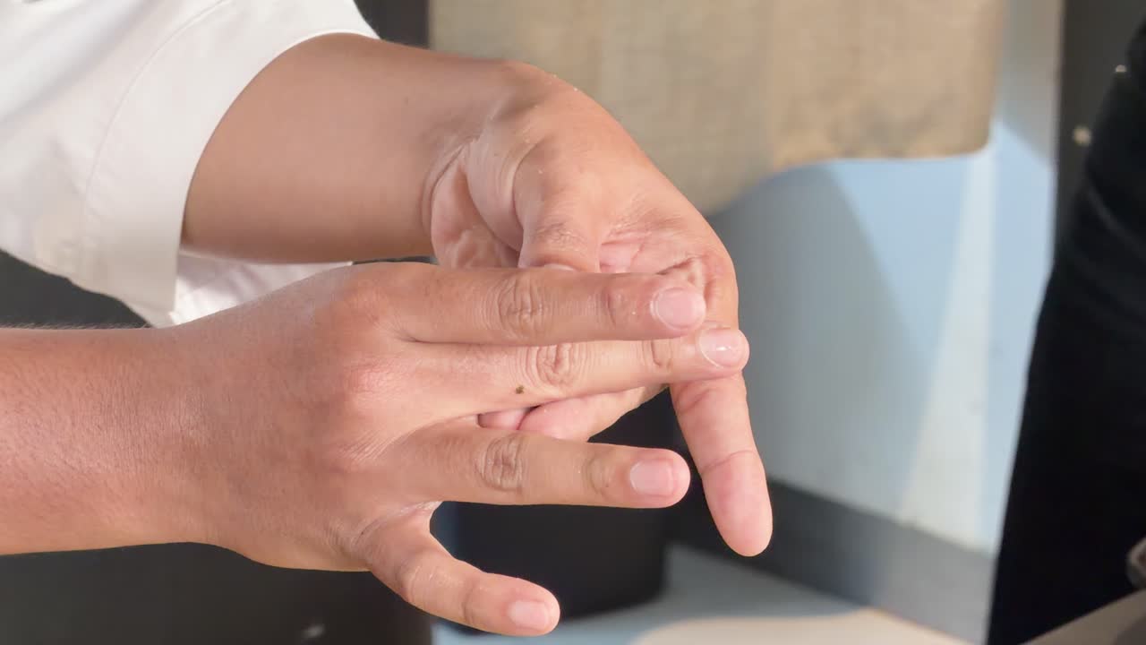 Primo piano delle mani di uno chef giapponese che insegna una precisa tecnica culinaria in una cucina con illuminazione soffusa