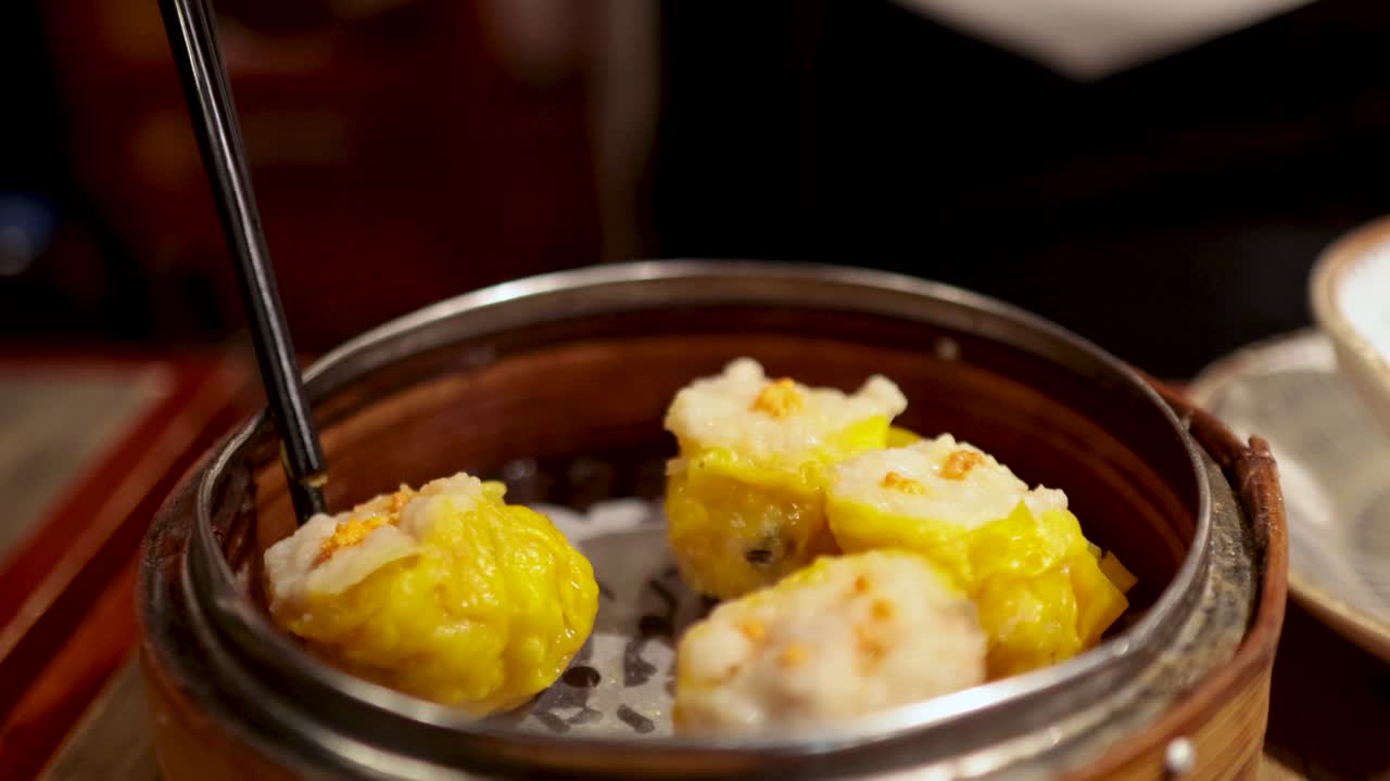 Chopsticks picking dumplings from a bamboo steamer