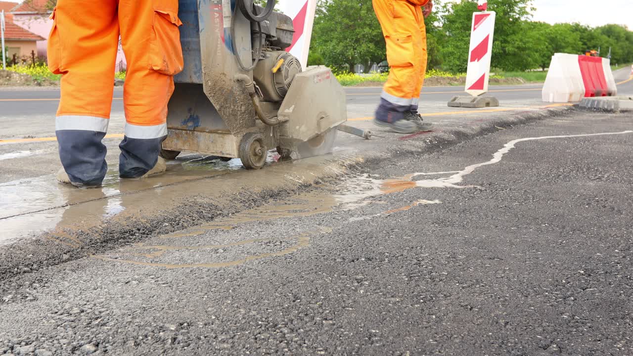 작업자 는 전기 도구 를 사용 하여 아스팔트 를 잘라서 올바른 측정 을 하고 있다