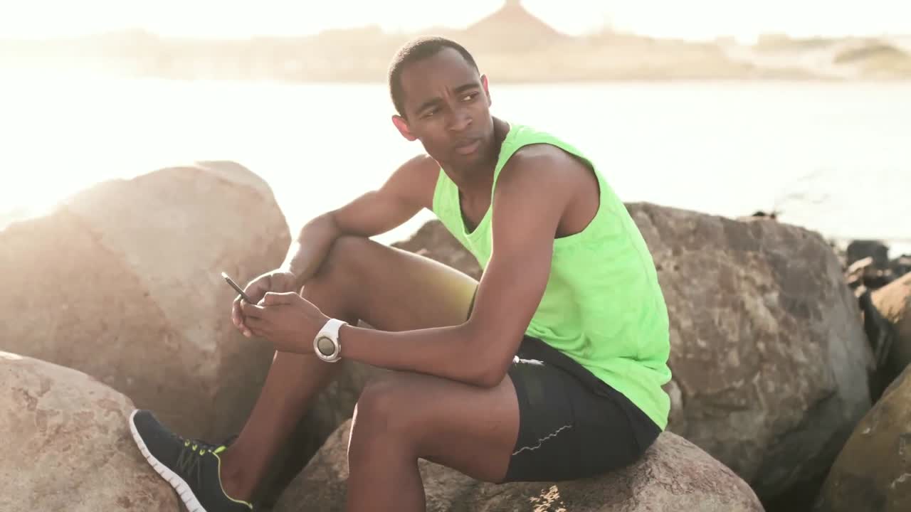 해변에서 스마트폰을 사용하는 남자