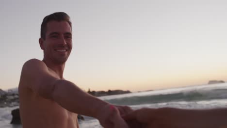una joven pareja de adultos relajándose en la orilla del mar