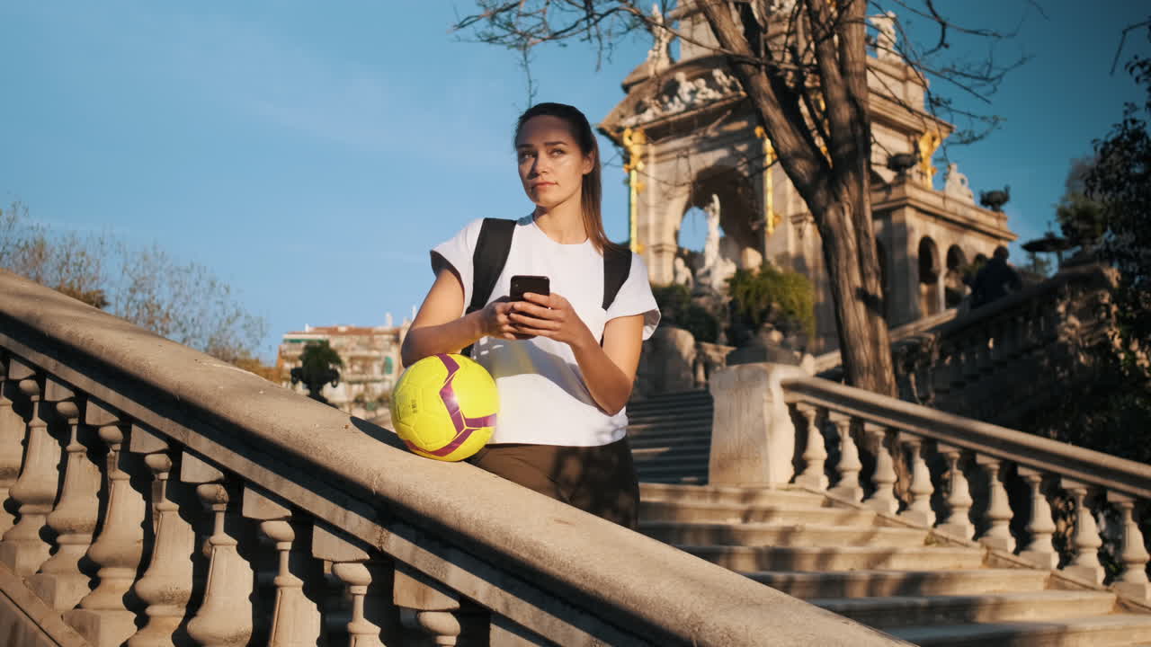 una hermosa jugadora de fútbol usando un teléfono inteligente.