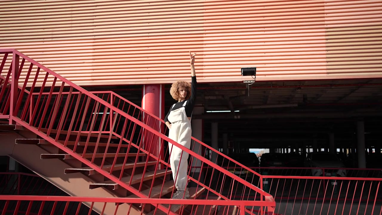 Una donna elegante posa con grazia su una suggestiva scala rossa in un contesto urbano.
