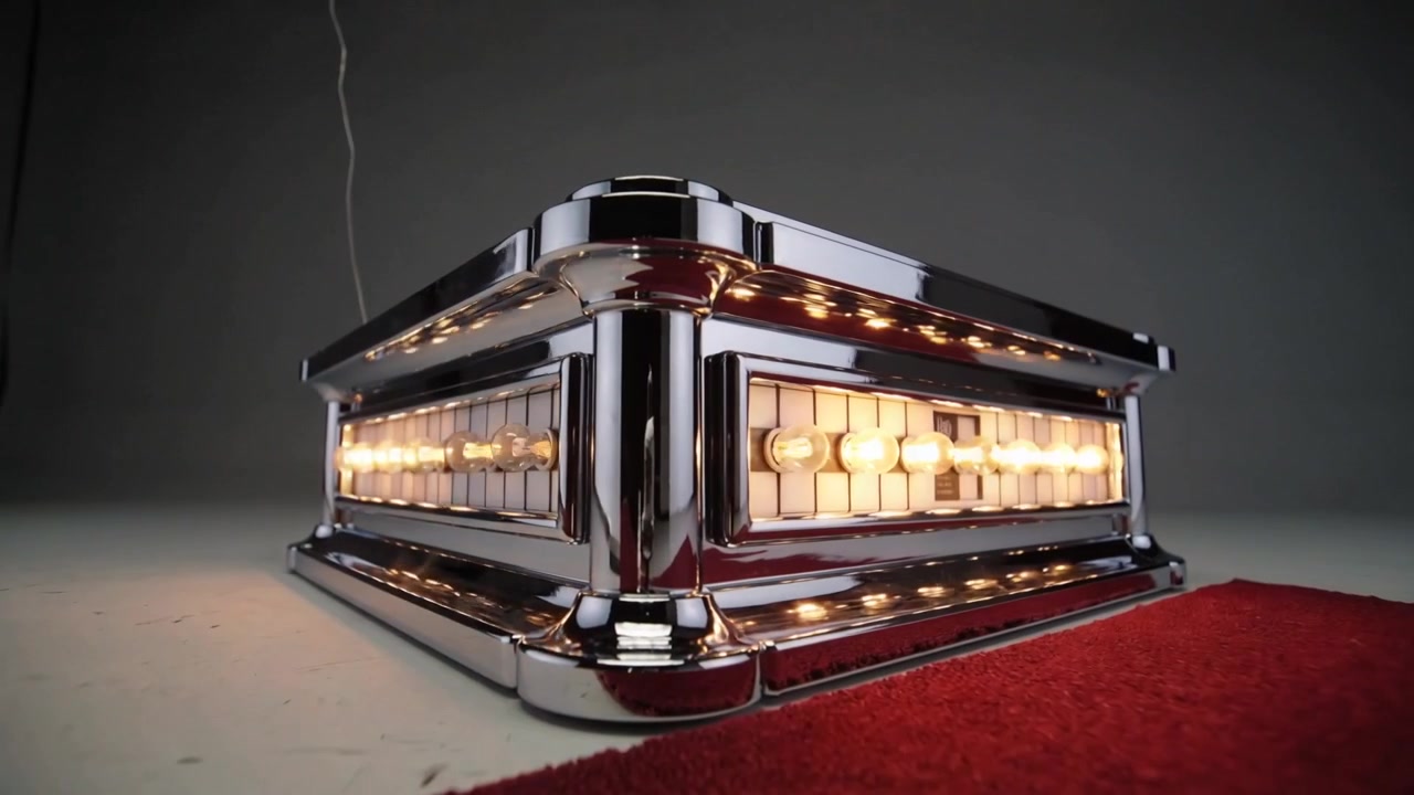 Powering chrome unit, bulbs lighting left-right at studio table, camera rising, showing reflections