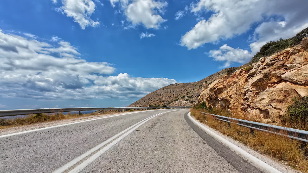 Vista del conducente di una strada di montagna in una giornata di sole in Grecia.