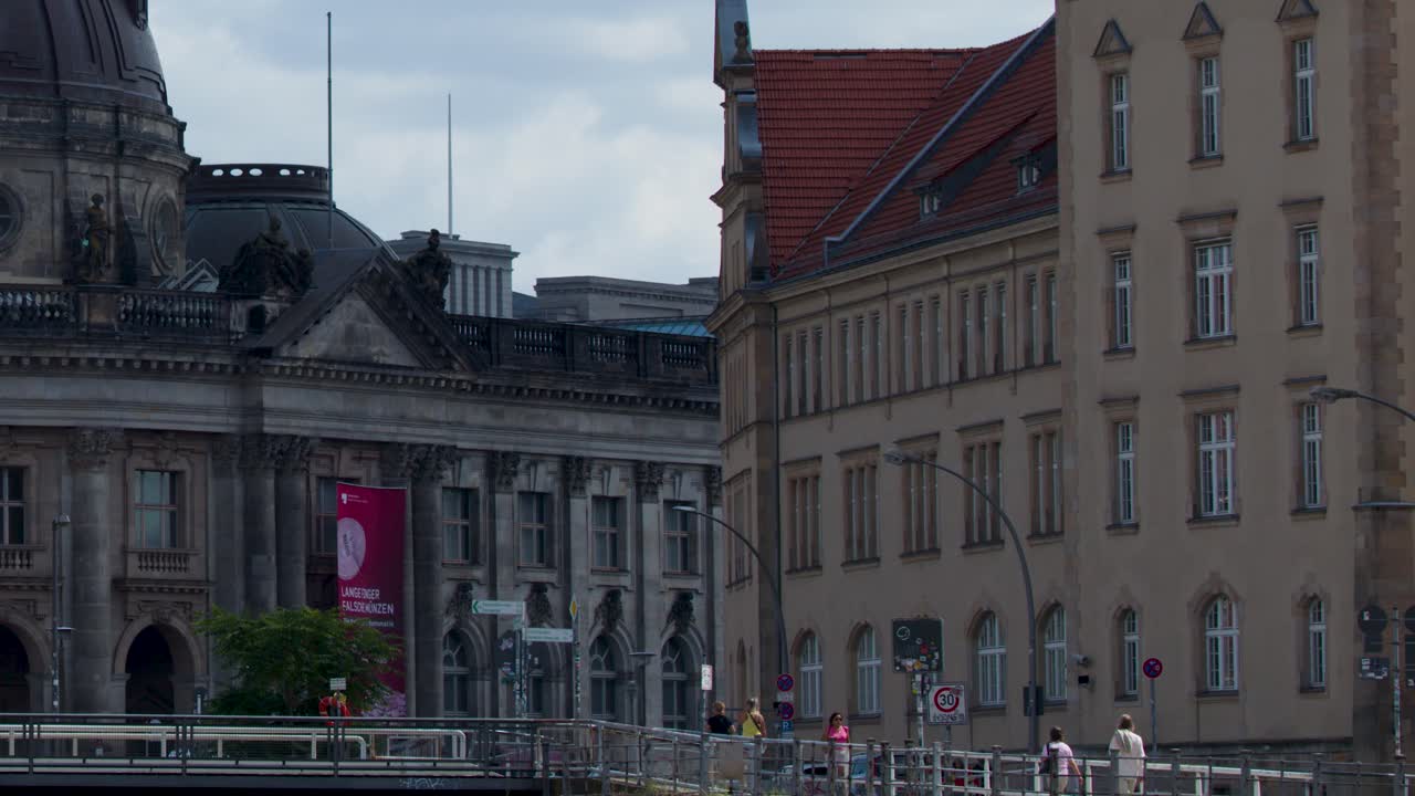Daytime camera pan reveals Bode Museum, pedestrians, and Spree River under partly cloudy sky