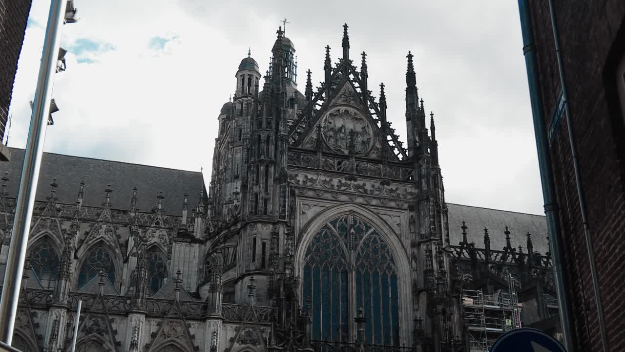 Carrellata attraverso una strada stretta verso la facciata di una cattedrale gotica nel centro di Den Bosch