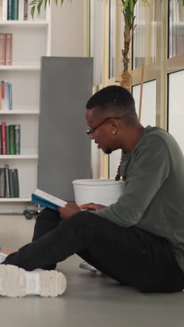 readers club meeting in public library. young women and black man with books sit on floor in bookstore. friends enjoy interesting literature together