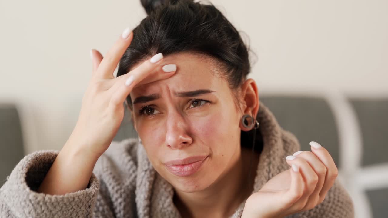 Ritratto di una bella giovane donna che guarda in camera esaminando la pelle problematica