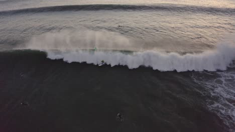 Aerial-tilt-up,-drone-shot-of-waves-on-the-atlantic-sea,-at-sunset,-in-Praia-sao-pedro-do-estoril,-on-a-sunny-evening,-in-Cascais,-Portugal