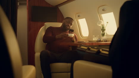 happy man browsing internet in first class. cheerful passenger drinking coffee