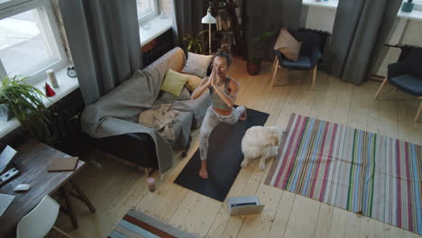 woman doing yoga at home with dog