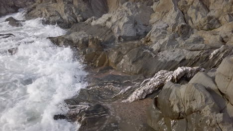 close up of waves breaking at a rocky beach during sunset