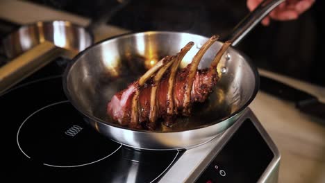 chef preparando costillas de cordero fritas en la sartén
