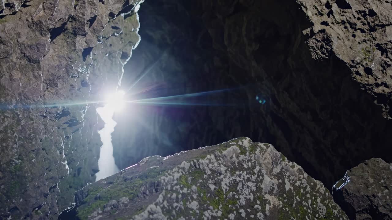 Close-up video shot of moss-covered rocks in a dimly lit cave, highlighting texture and natural