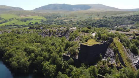 aerial view welsh woodland valley slate mining shaft and snowdonia mountains revealing quarry lake