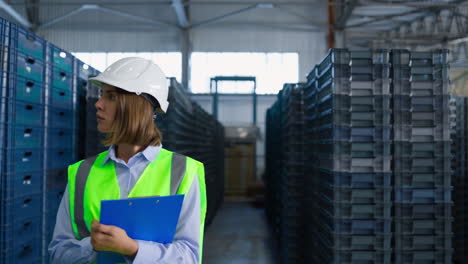 female storage employee inspecting blue delivery boxes managing factory shipment