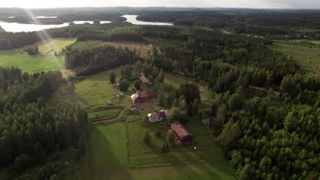 Vista-Aérea-De-Casas-De-Campo-En-Un-Hermoso-Ambiente-De-Puesta-De-Sol-En-El-Campo,-Finlandia,-Kuopio,-Vehmersalmi,-Impresionante-Bosque-Y-Paisaje-Lacustre