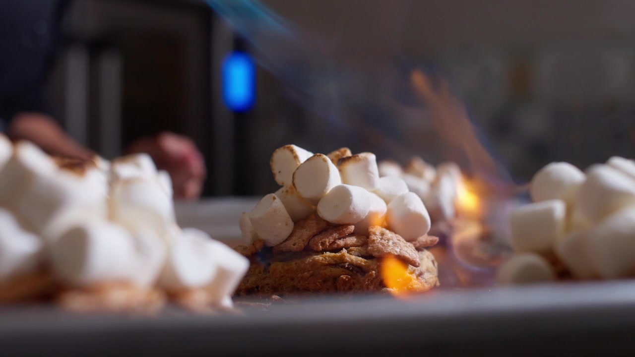Witte marshmallows gestapeld op koekjes vertonen licht geroosterde randen op een metalen bakplaat.