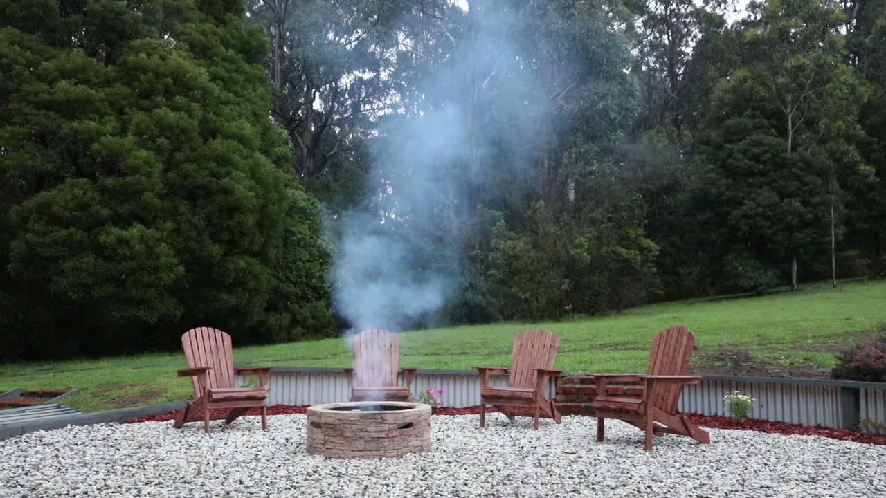Seamless loop of smoke gently rising from a fire pit in a cozy backyard setting