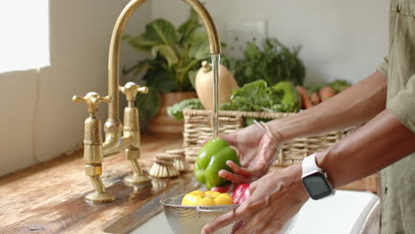 washing fresh red and yellow bell peppers in kitchen sink with running water, at home