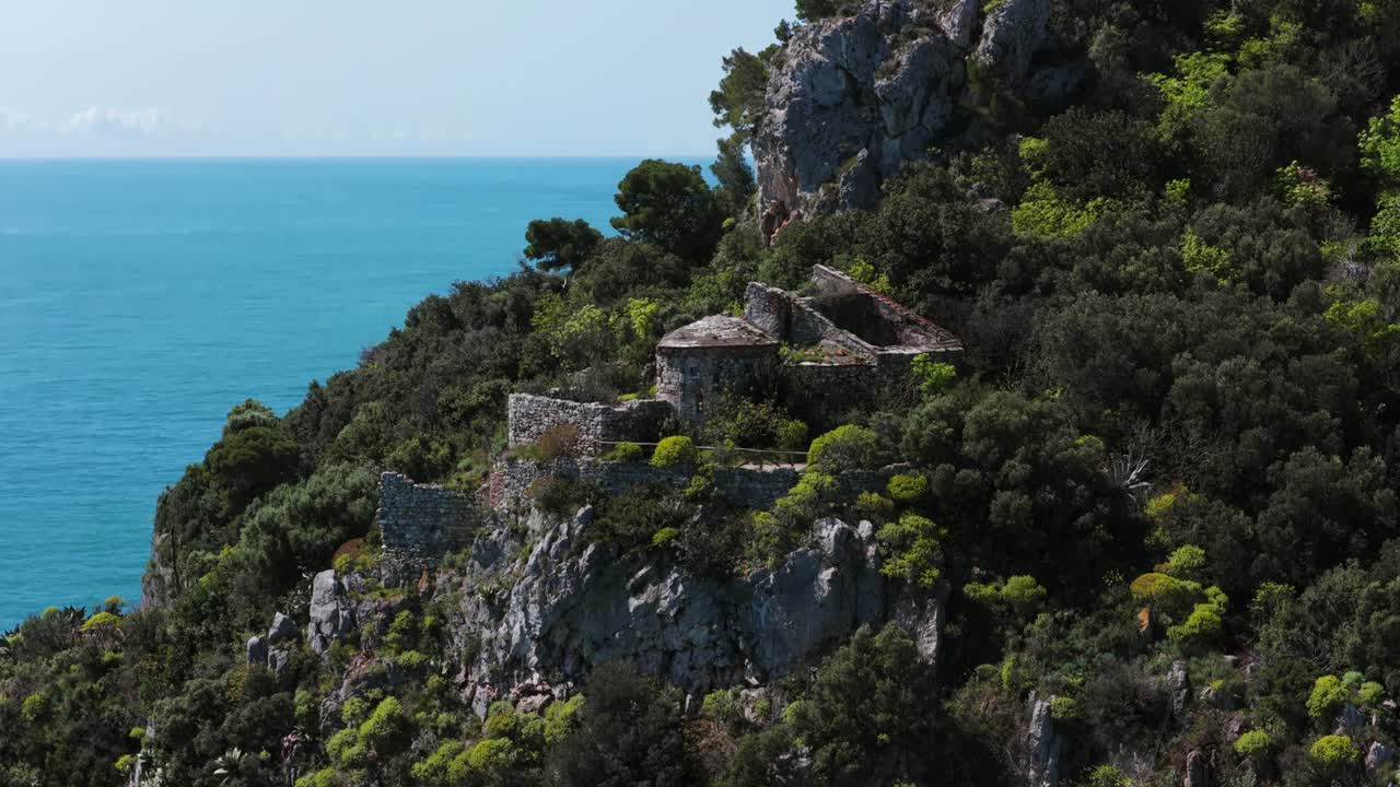 Aerial drone approaches dramatic sea stack (Lo Scoglio) and cliffs at Capo Noli, pristine turquoise waters of Ligurian Sea, Riviera, Italy