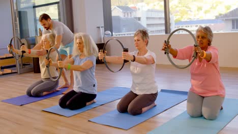 Trainer-assisting-senior-women-in-performing-yoga-4k