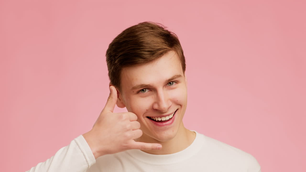 Smiling young man making a phone gesture