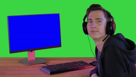 jugador emocionado con auriculares sonriendo a la cámara en una pantalla verde, clave de croma
