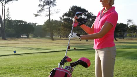 female golfer removing golf club from golf bag