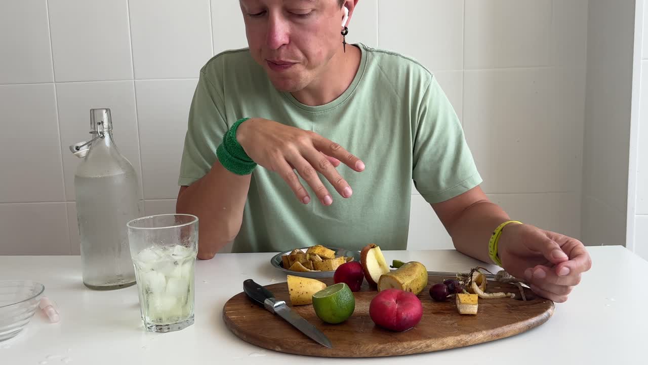 Uomo che mangia frutta fresca e formaggio con acqua a tavola