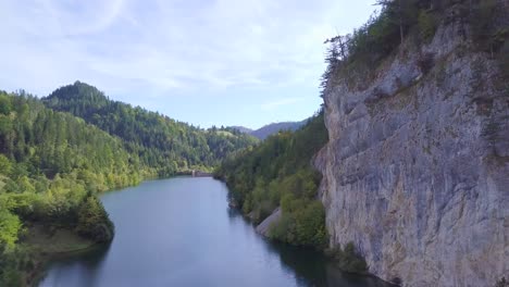 Impresionante-Toma-Aérea-Ascendente-De-4k-De-Un-Pequeño-Lago-En-Montañas-Con-Bosque-Verde