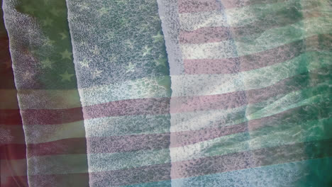 Digital-composition-of-waving-us-flag-against-aerial-view-of-the-sea-waves